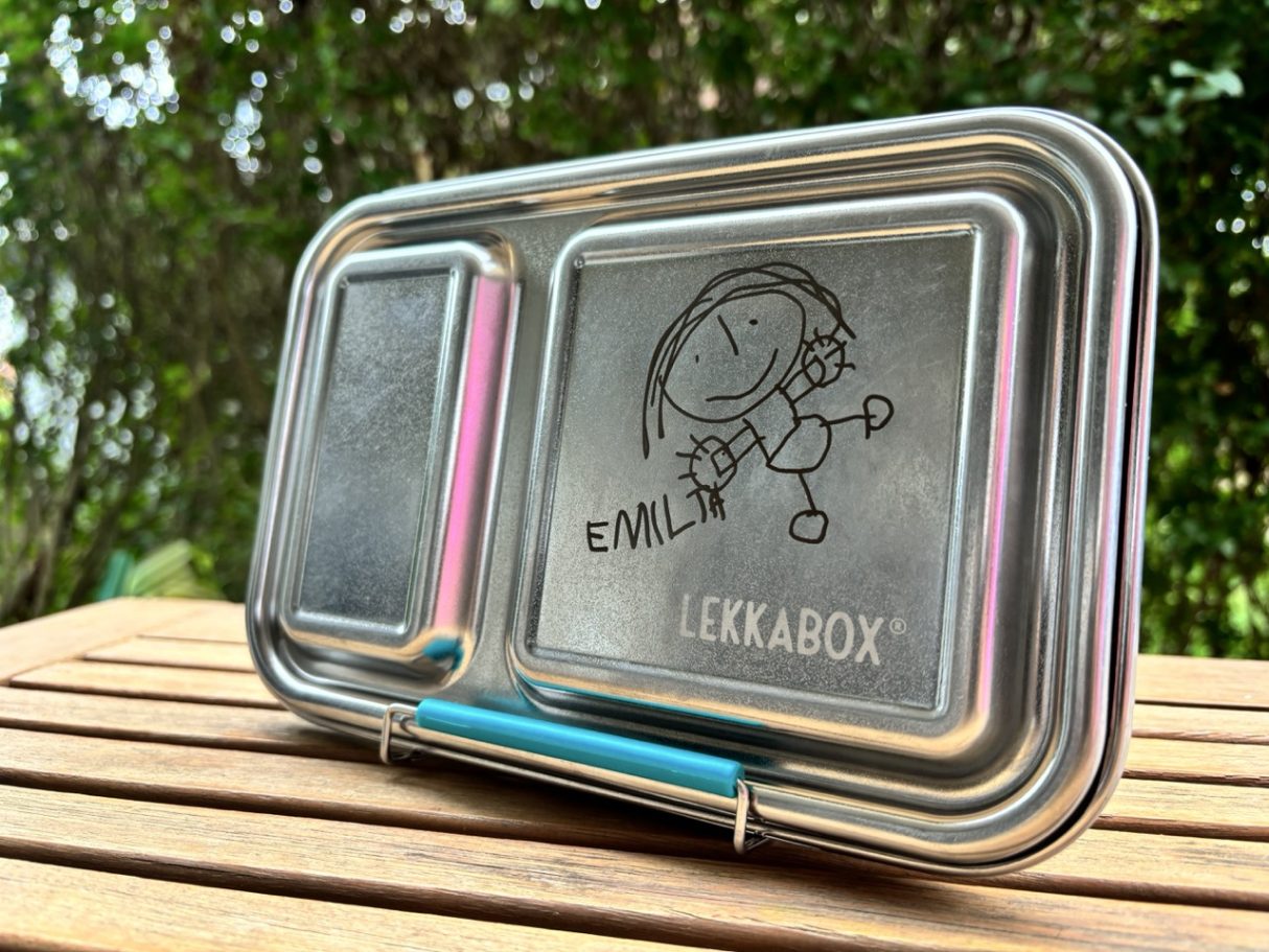 Brotbox mit individueller Kinderzeichnung Edelstahlplatte mit eingeätztem Cartoon-Motiv und buntem Stift-Clip.
