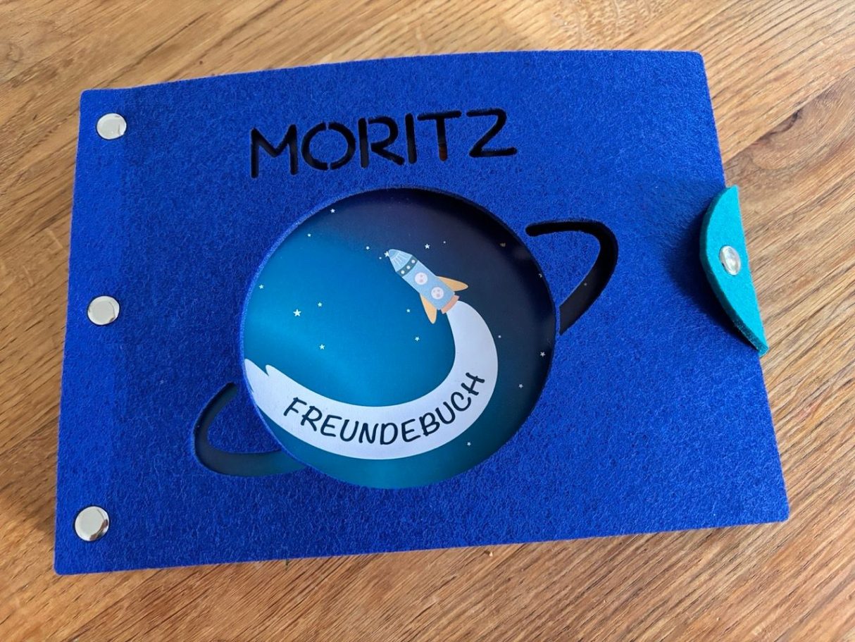 Freundebuch Weltall Blaues Album mit dem Namen „Moritz“ und einem Motiv von einer Rakete im Weltall.
