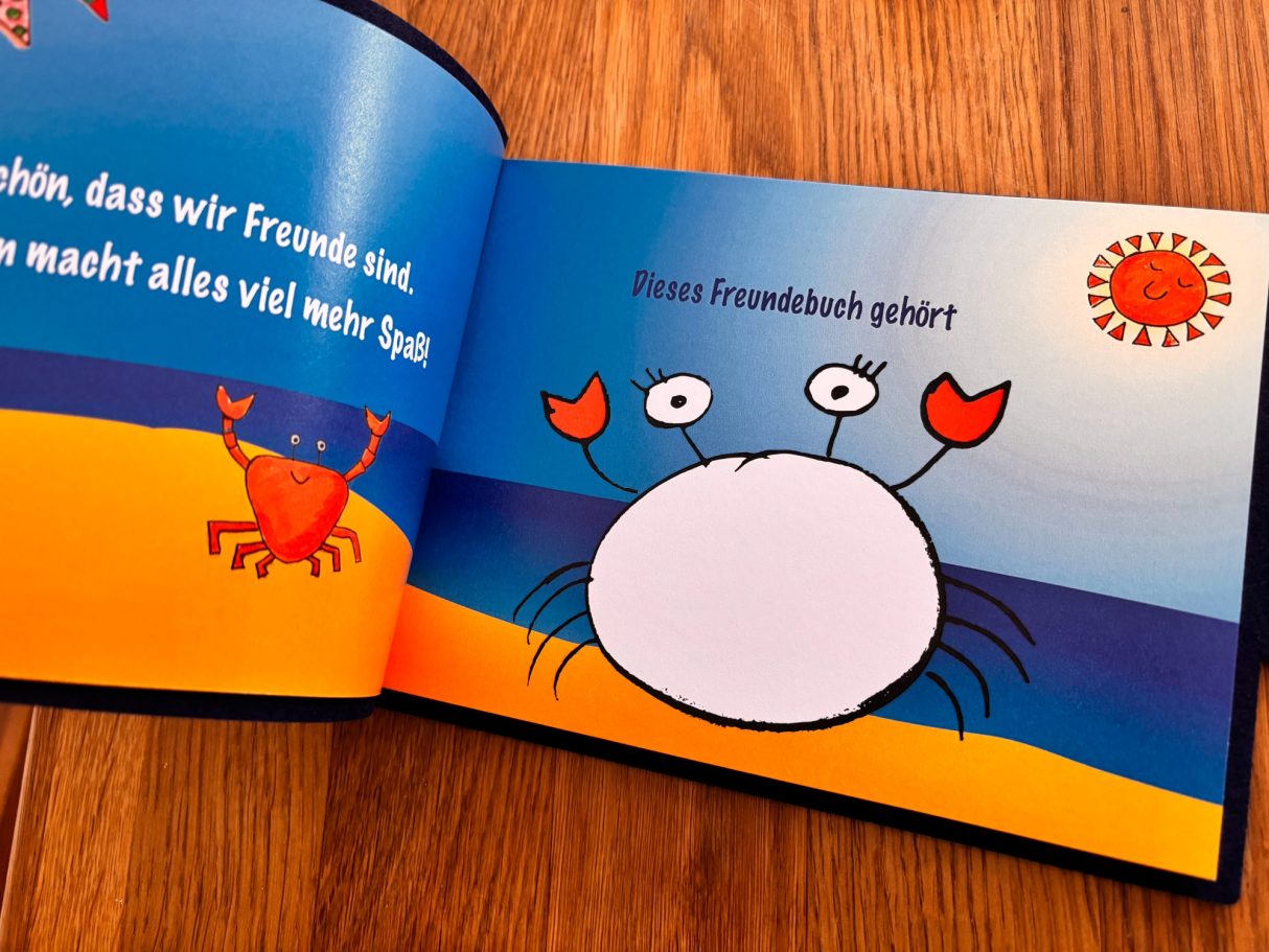 Freundebuch Nordsee Bunte Kinderbuchseite mit einem Strand, einer Sonne und einer Krabbe.