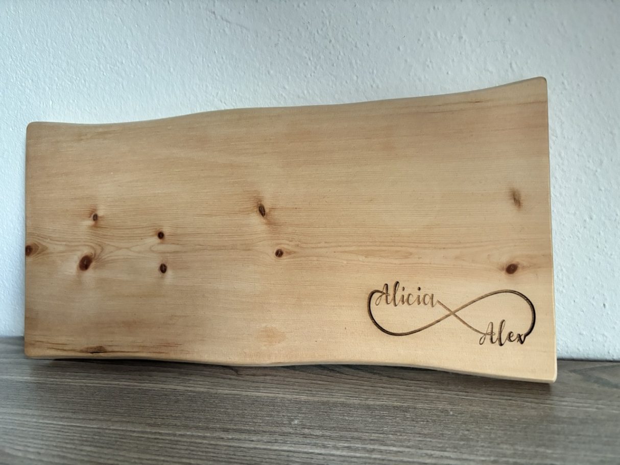 Zirbenholzbrett mit Gravur Holzbrett mit geschwungener Form und eingravierter Unendlichkeitsschleife.