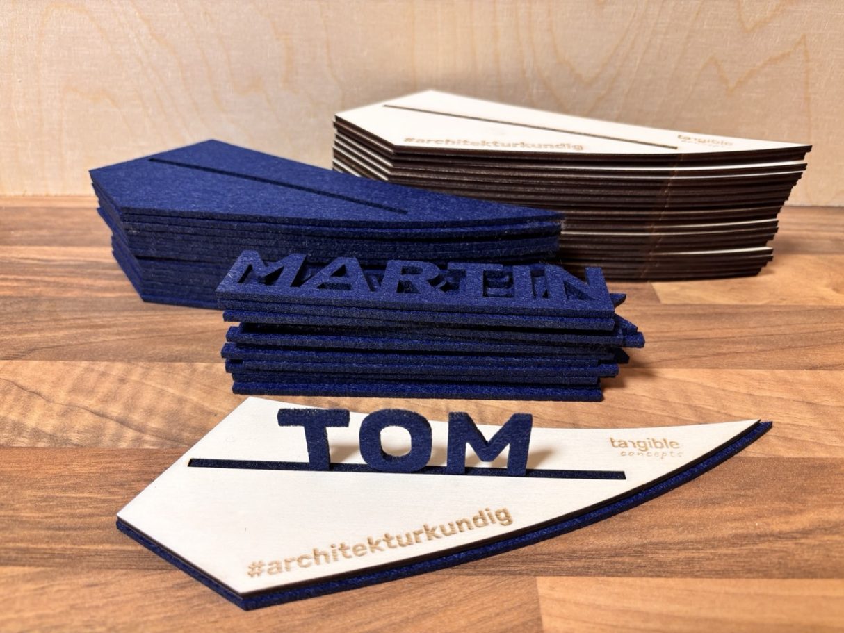 Namensschilder Bunte Namensschilder aus Holz, mit den Namen "MARTIN" und "TOM" in verschiedenen Schriftarten.