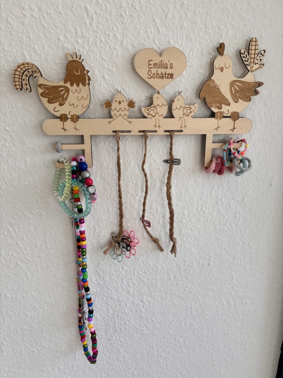 Schmuckaufbewahrung im Hühnerdesign Holzhalter mit Hühner-Motiven und bunten Schnüren zum Aufhängen.